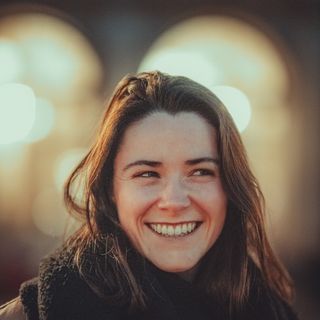 A woman in her thirties smiling outdoors.